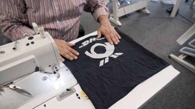 DHL Group und Moot launchen Upcycling-Kollektion aus Unternehmenskleidung - Ein Moot-Mitarbeiter näht aus einem alten DHL-Shirt etwas Neues - Quelle: DHL Group